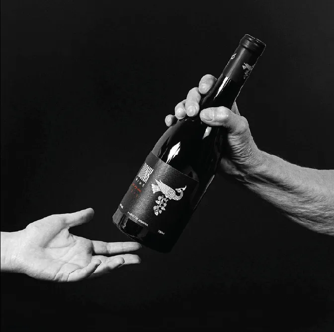 Toonk Wine bottle passed between two hands