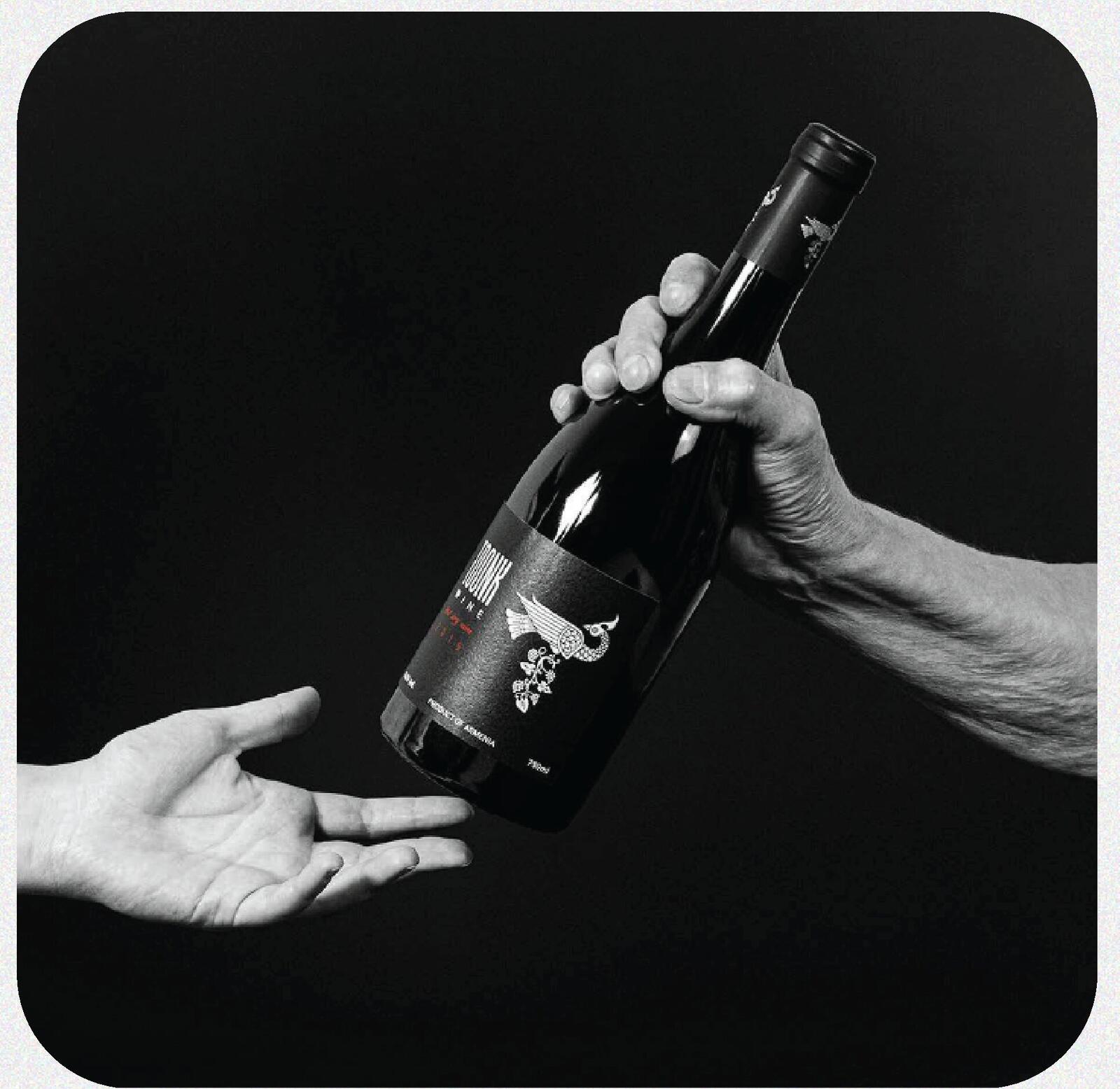 Toonk Wine bottle passed between two hands